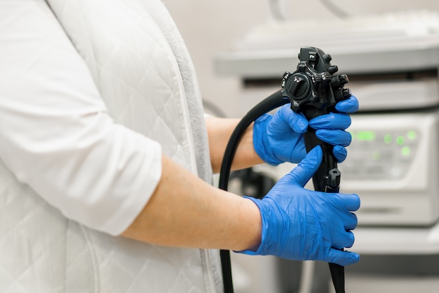 Close up doctor's gloved hand with endoscope during diagnostic gastroscopy or colonoscopy in clinic